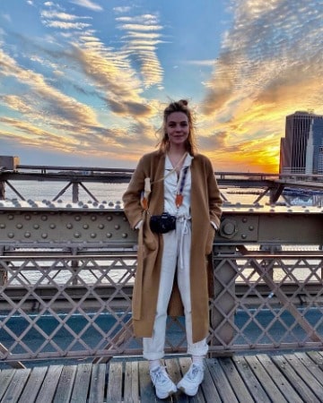 Picture of Eloise Mumford in brown jacket with beautifull sun-set background view.